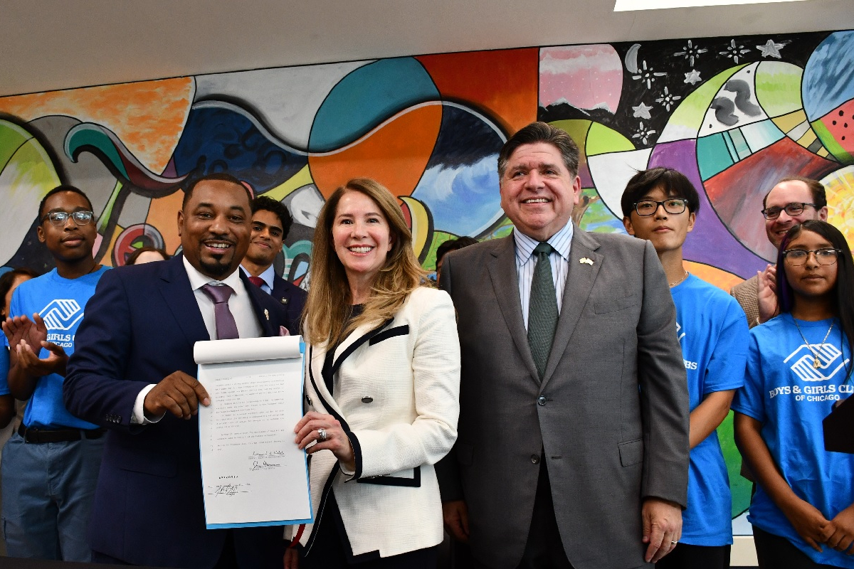 State Senator Willie Preston and State Representative Jennifer Gong-Gershowitz hold House Bill 5511 as they stand next to Governor JB Pritzker and members of the Boys & Girls Club of Chicago